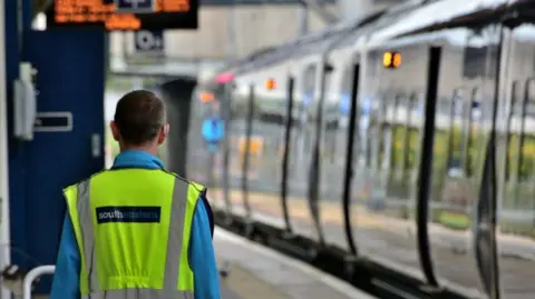 Southeastern Railway A Southeastern train arriving at a station, as a member of staff in hi vis jacket watches on