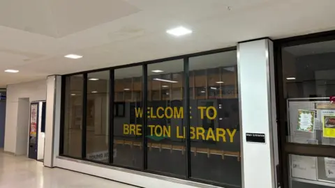 Shariqua Ahmed/BBC Exterior of Bretton Library - glass window with a yellow "Bretton Library" sign