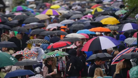 PA Media People taking shelter from the rain during the RHS Chelsea Flower Show