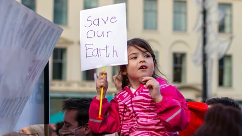 Getty Images Girl holding "save our earth" sign at climate change protest (Credit: Getty Images)