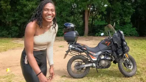 Udoh Ebaide Joy Udoh Ebaide Joy standing in front of her motorcycle