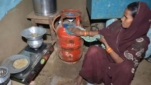 Getty Images In this photograph taken on April 8, 2019, Indian women Reena Devi (C) cleans a gas cylinder as she prepares food on a gas stove in Nisarpura village on the outskirts of Patna. - Reena Devi says her life changed when she got a cooking gas connection under a programme championed by India's Prime Minister Narendra Modi.