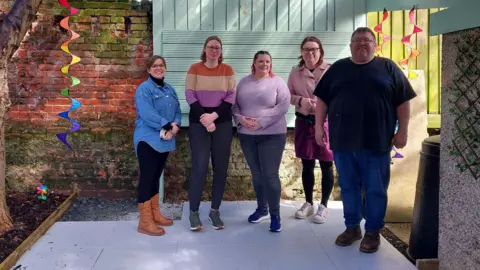 Rippleacts CIC A group of people standing in a outdoor space that has been recently updated