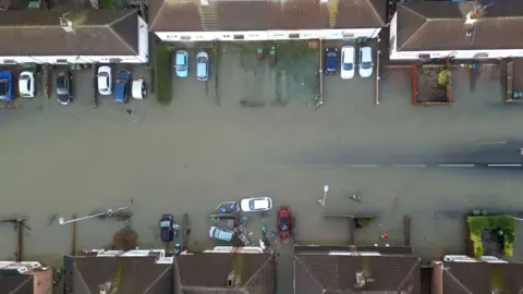 PA Media An aerial photograph of houses and homes surrounded by flood water