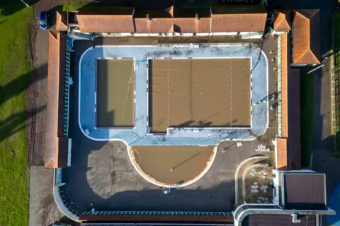 Getty Images An aerial view of Pontypridd Lido showing the red tile of the changing rooms and the blue tiling poolside. But the water is brown.