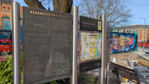 A permanent sign outside Derby Market Hall, with information about the connection between Osnabruck, in Germany, and Derby