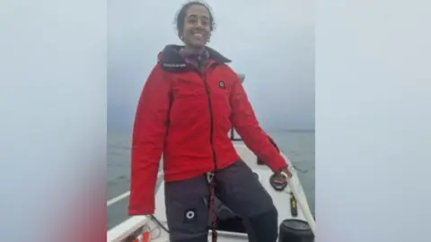 Ananya Prasad Ananya Prasad smiling as she stands on her boat in the ocean