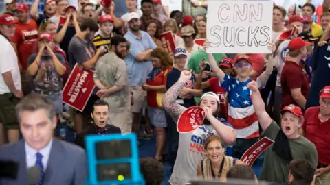 Getty Images People shout behind CNN reporter Jim Acosta before a campaign rally for South Carolina Governor Henry McMaster featuring President Donald Trump at Airport High School June 25, 2018