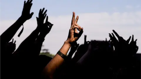 Lucas Ninno/Getty hands in the air at a generic music festival